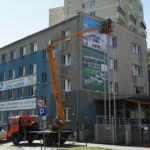 Montaż banera na dużej wysokości przy użyciu podnośnika